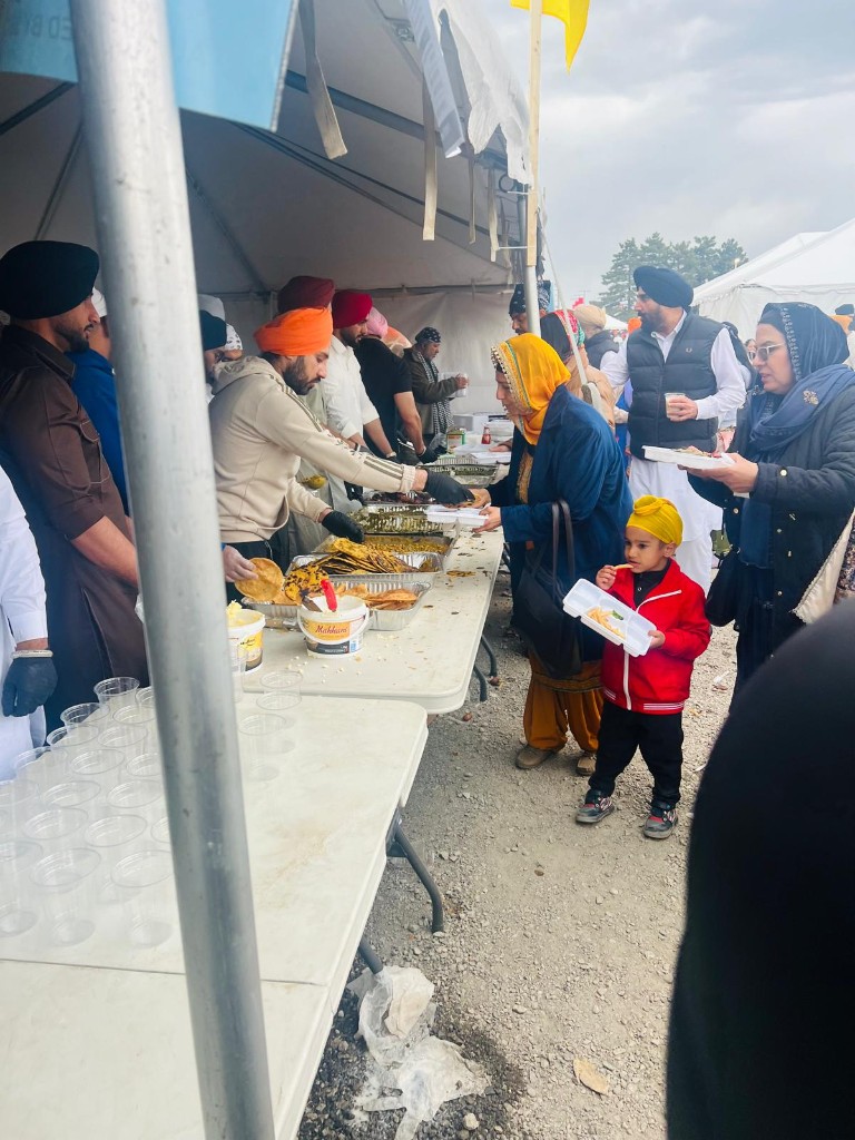 Outdoor langar seva serving food to the community under a tent